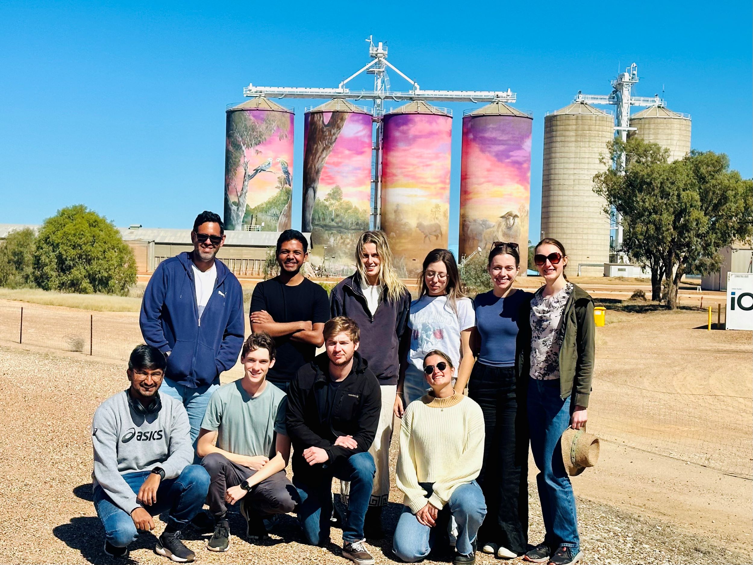 9 students standing in front of painted silos in St George
