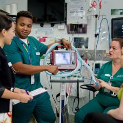 Four doctors discussing piece of equipment in hospital
