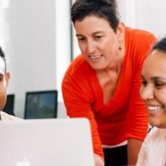Two university students looking at laptop while lecturer looks over their shoulder. Image, UQ