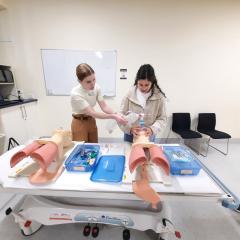 Doctor demonstrating how to use breathing equipment to student on mannequin